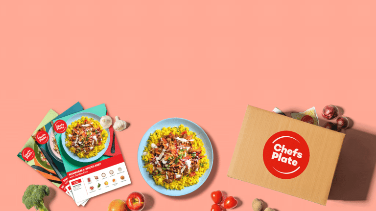 A vibrant and enticing Chefs Plate promotional image, featuring a delicious plate of shawarma-spiced beef over golden rice. The plate is surrounded by an array of fresh ingredients like apples, garlic, and onions, as well as Chefs Plate recipe cards, hinting at the easy-to-follow instructions that come with each meal kit. On the right, a Chefs Plate box brimming with fresh produce and ingredients, proudly displays the Chefs Plate logo, inviting viewers to explore their meal kit options. This image captures the essence of the convenience and flavor that the Chefs Plate promo code offers to first-time users looking to delve into home-cooked culinary delights.