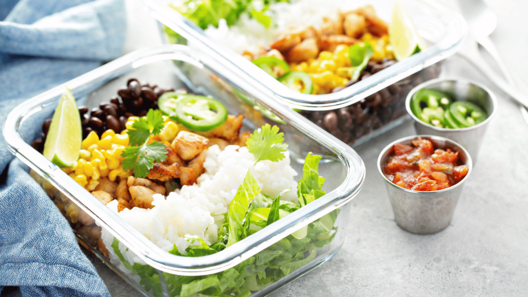 Healthy meal prep containers with a variety of fresh ingredients including corn, black beans, cilantro, rice, and diced chicken, representing convenient and nutritious Vancouver meal delivery services.