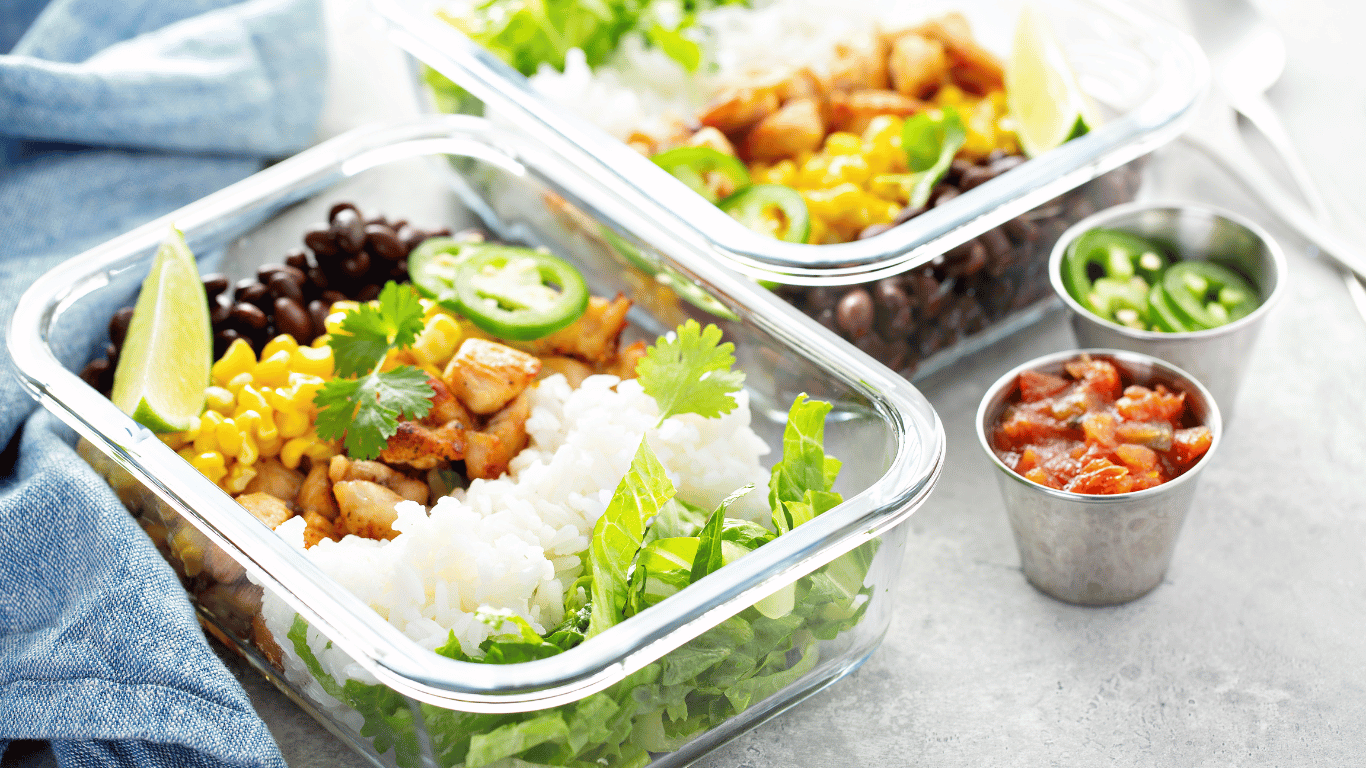 Healthy meal prep containers with a variety of fresh ingredients including corn, black beans, cilantro, rice, and diced chicken, representing convenient and nutritious Vancouver meal delivery services.